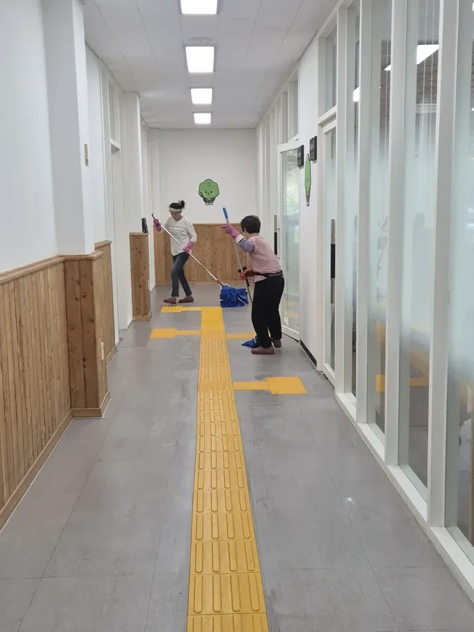 복도에서 대걸레로 바닥을 닦는 두 명의 작업자
